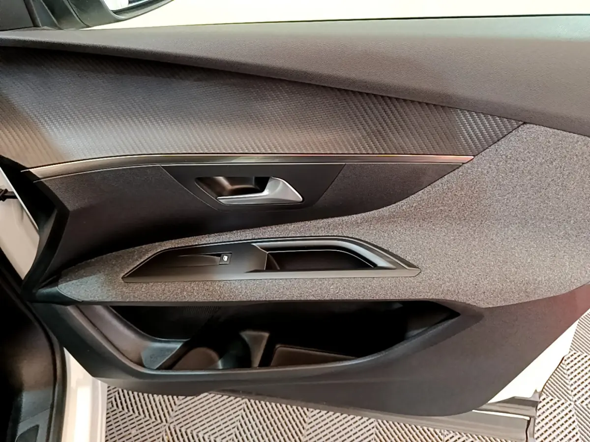 Détail de la porte côté gauche intérieure du Peugeot 3008 blanc, avec poignée et commande de vitre noire.