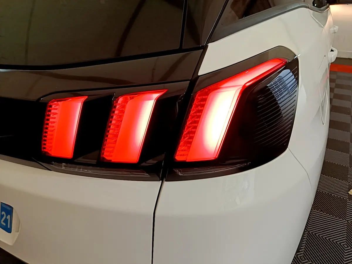 Gros plan sur le feu arrière droit rouge du Peugeot 3008 blanc, soulignant la finition moderne et les lignes nettes du coffre.