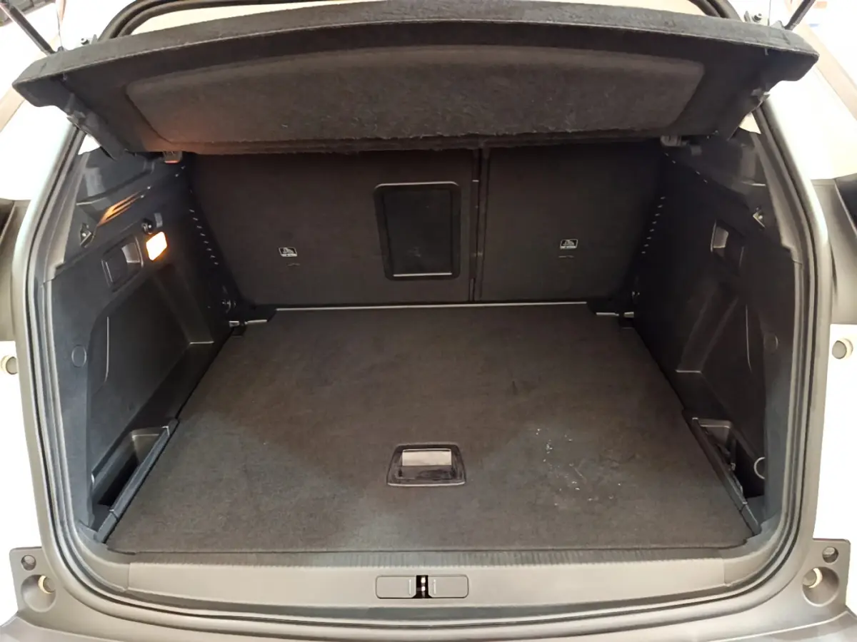 Coffre ouvert d'un Peugeot 3008 blanc, vue arrière montrant l'espace de chargement vide et tapis noir.