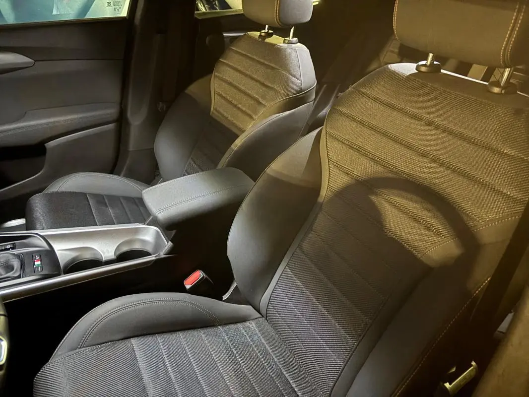 Vue intérieure rapprochée des sièges avant sport noirs de l'Alfa Romeo Tonale 2023, avec accoudoir central et console.