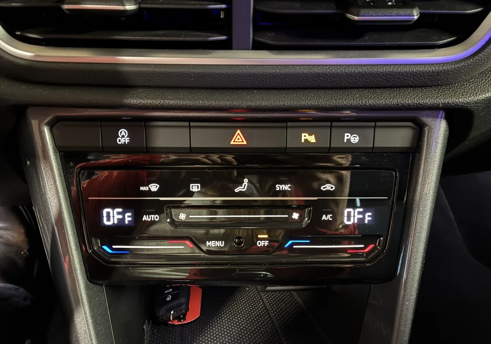 Vue rapprochée du tableau de bord du Volkswagen T-Roc gris 2023, mettant en valeur la console de climatisation digitale éteinte.