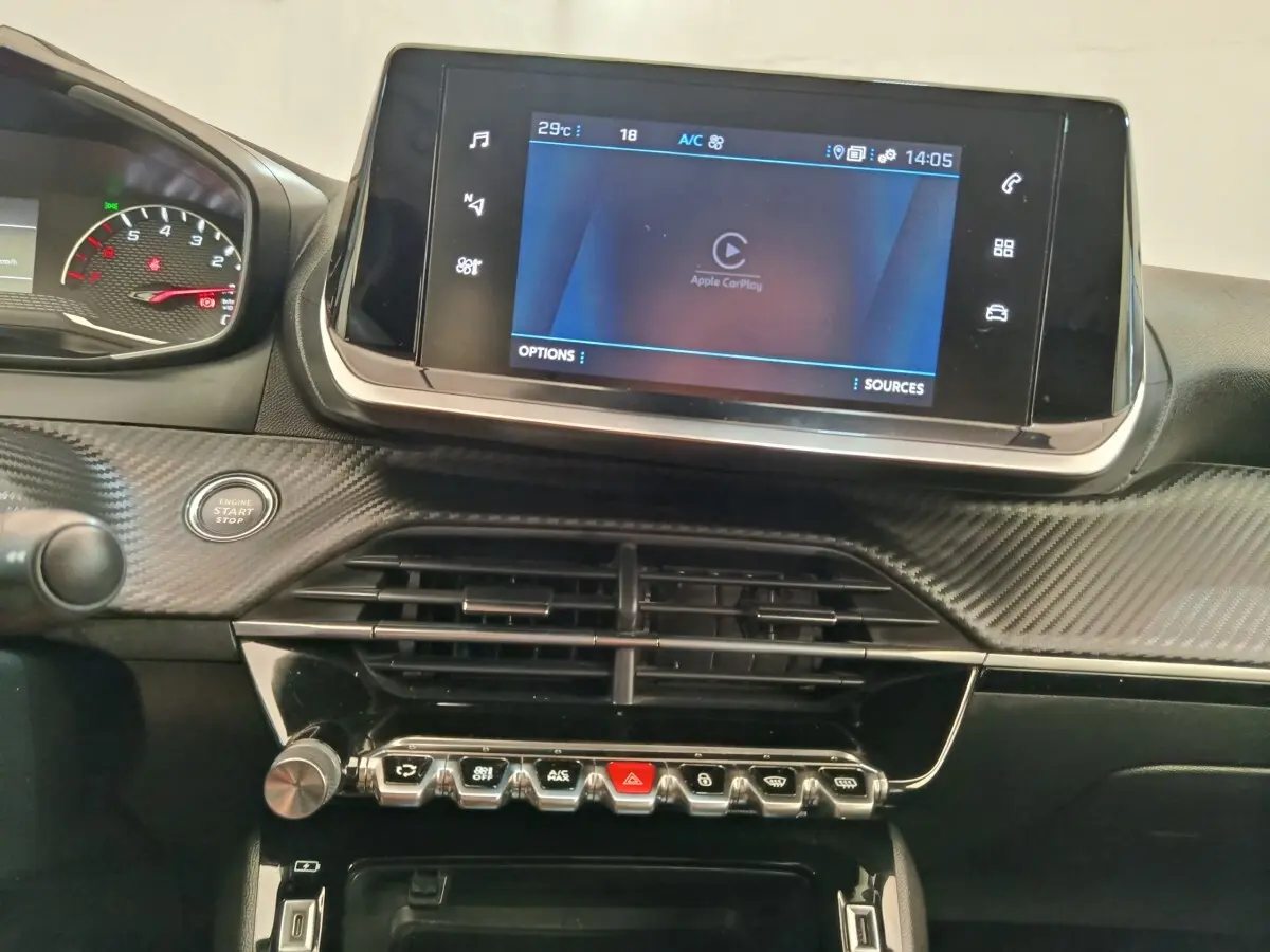 Vue rapprochée du tableau de bord du Peugeot 2008 bleu 2021, avec écran tactile Apple CarPlay et commandes en ligne.