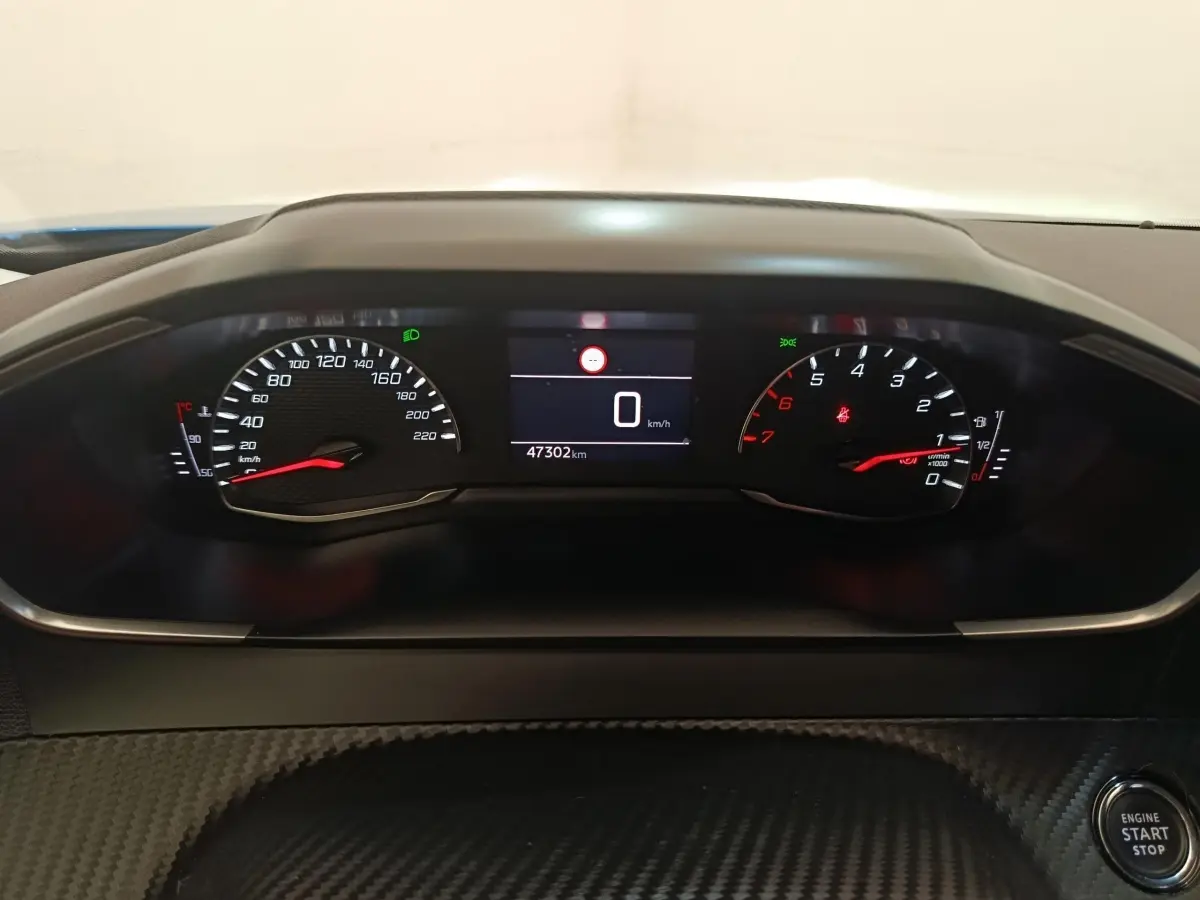Vue rapprochée du tableau de bord de la Peugeot 2008 bleu, affichant le compteur et le bouton démarrage.