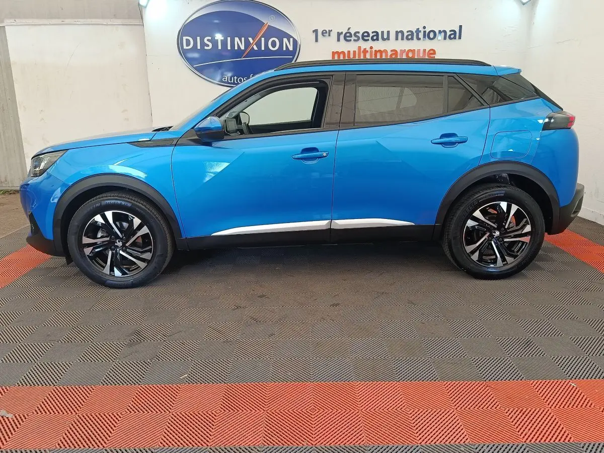 Vue de profil côté gauche d’un Peugeot 2008 bleu 2021 avec jantes alliage noires et toit noir contrasté.