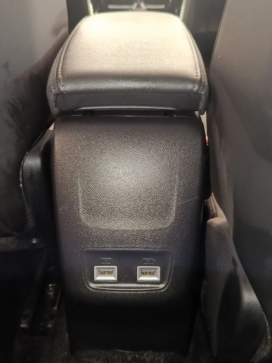 Vue rapprochée de la console centrale arrière noire avec deux ports USB dans un Peugeot 2008 bleu 2021.