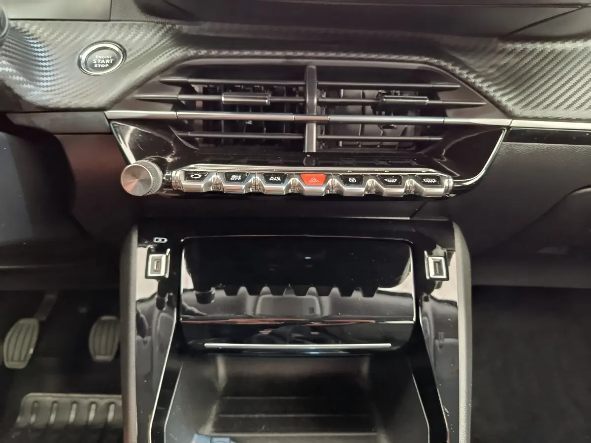 Vue rapprochée de la console centrale noire du Peugeot 2008 avec boutons chromés et bouton démarrage Start/Stop.
