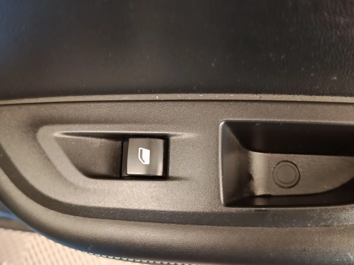 Gros plan sur le bouton de commande électrique de la vitre côté conducteur d’une Peugeot 2008 bleu 2021.