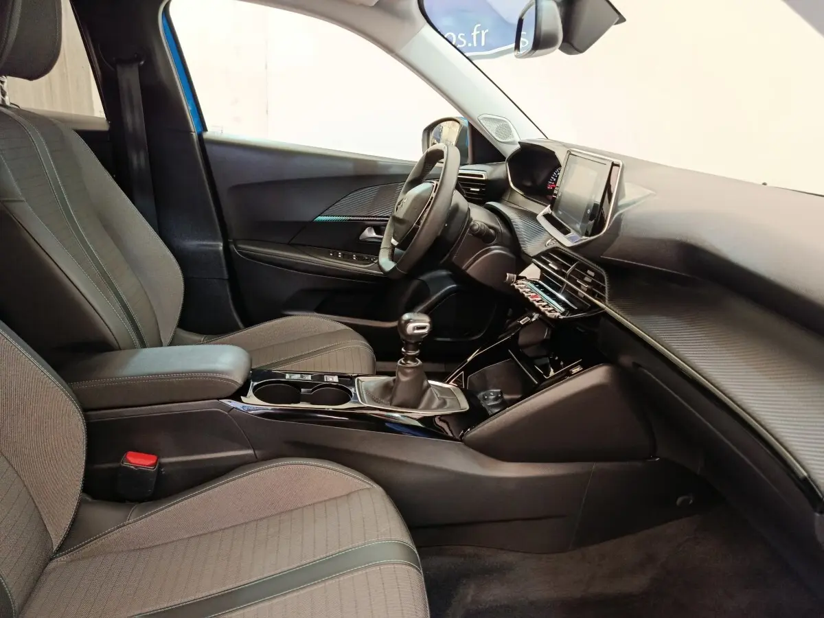 Vue intérieure côté conducteur du Peugeot 2008 bleu 2021, avec volant cuir multifonctions et tableau de bord moderne.