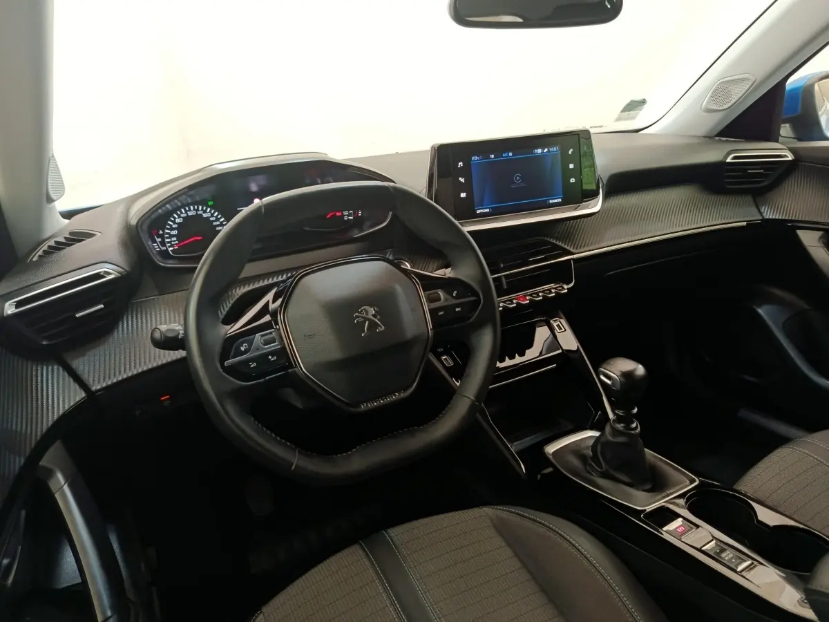 Vue intérieure avant du Peugeot 2008 bleu 2021, volant cuir multifonctions et écran tactile central visible.
