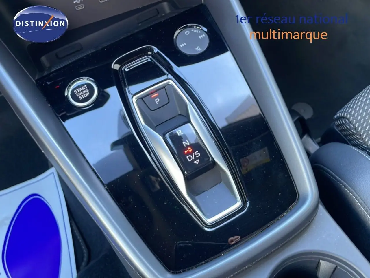 Gros plan sur la console centrale noire brillante avec levier de vitesses automatique et bouton start/stop dans l’Audi A3 Sportback blanche.