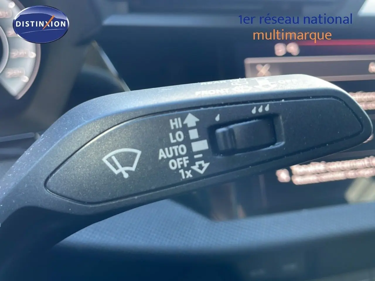 Gros plan sur la commande d’essuie-glace de l’Audi A3 Sportback 40 TFSIe blanche, intérieur avec affichage numérique flou.