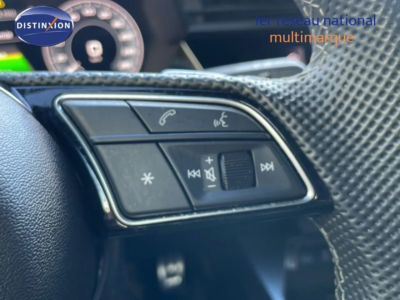 Gros plan sur les commandes multifonctions du volant en cuir noir de l'Audi A3 Sportback blanc ibis 2025.