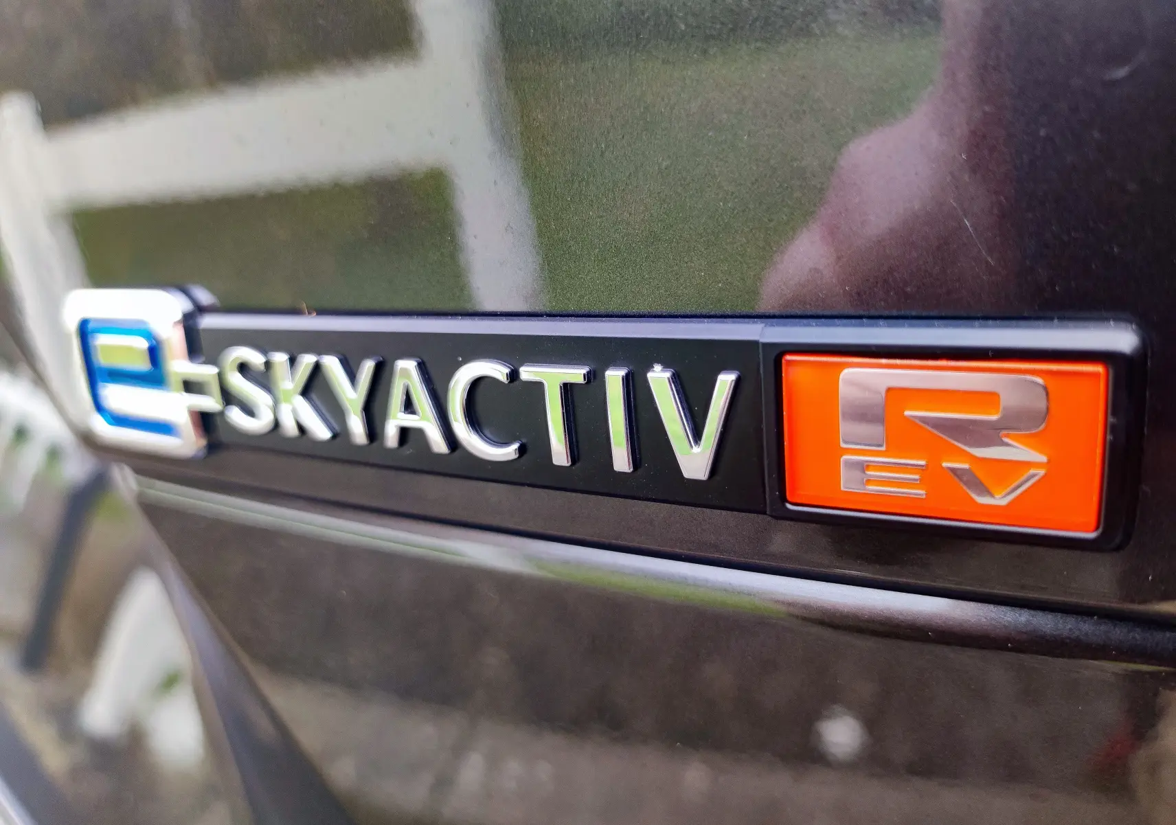 Gros plan sur le logo e-SKYACTIV R EV sur la carrosserie gris foncé d'une Mazda MX-30 hybride rechargeable 2023.