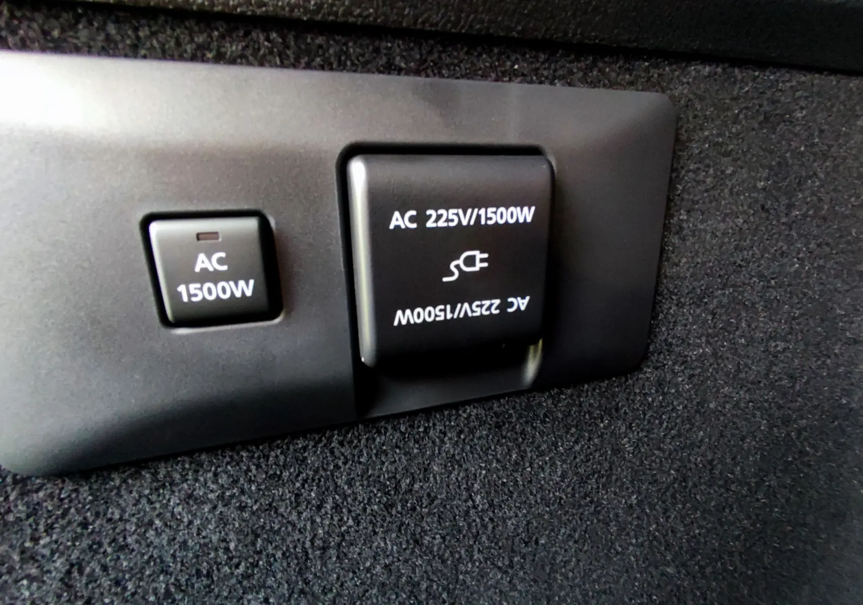 Prise électrique 225V/1500W en gros plan dans le coffre du Mazda MX-30 gris foncé hybride rechargeable 2023.