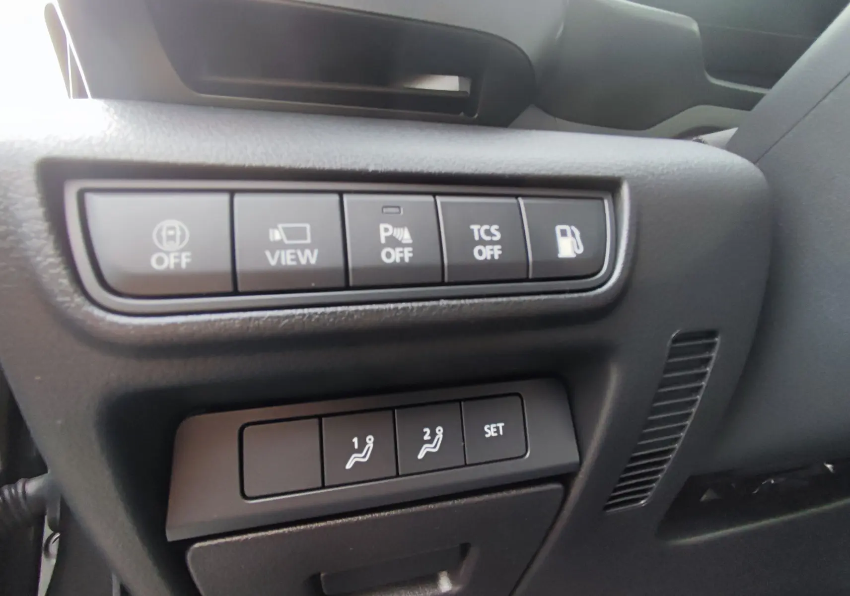 Panneau de commandes côté conducteur du Mazda MX-30 2023 gris foncé, avec boutons d'assistance et réglages de sièges mémoire.