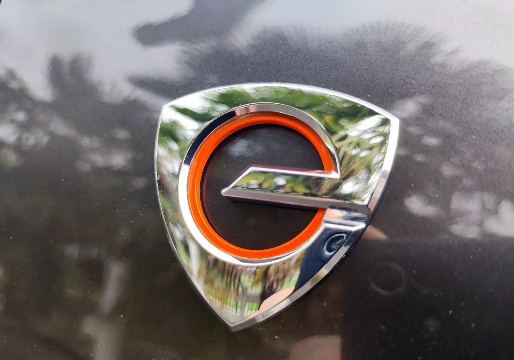 Gros plan sur le logo E-SKYACTIV orange et chromé sur la carrosserie gris foncé d'une Mazda MX-30 hybride rechargeable 2023.