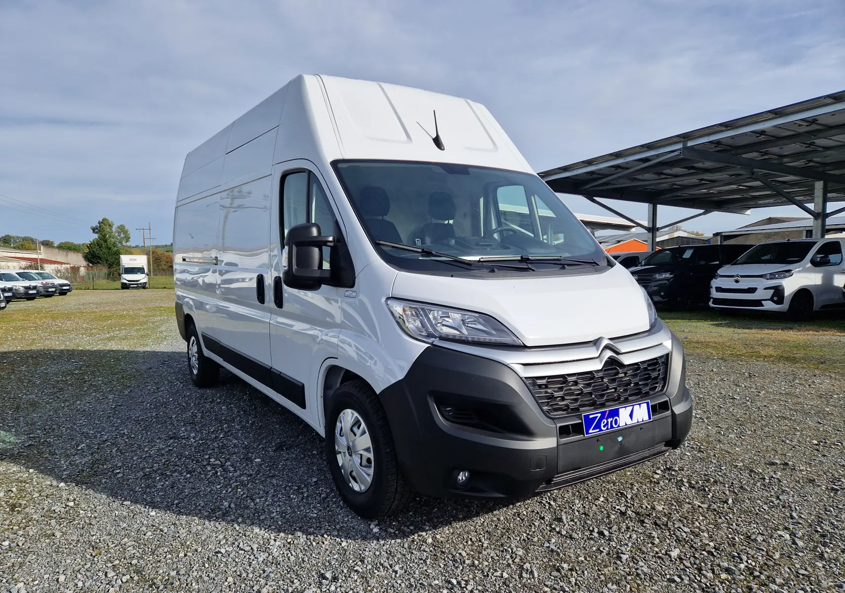 Vue 3/4 avant d’un utilitaire Citroën Jumper blanc L3H3, avec calandre noire et pare-chocs contrasté, sur un parking extérieur.