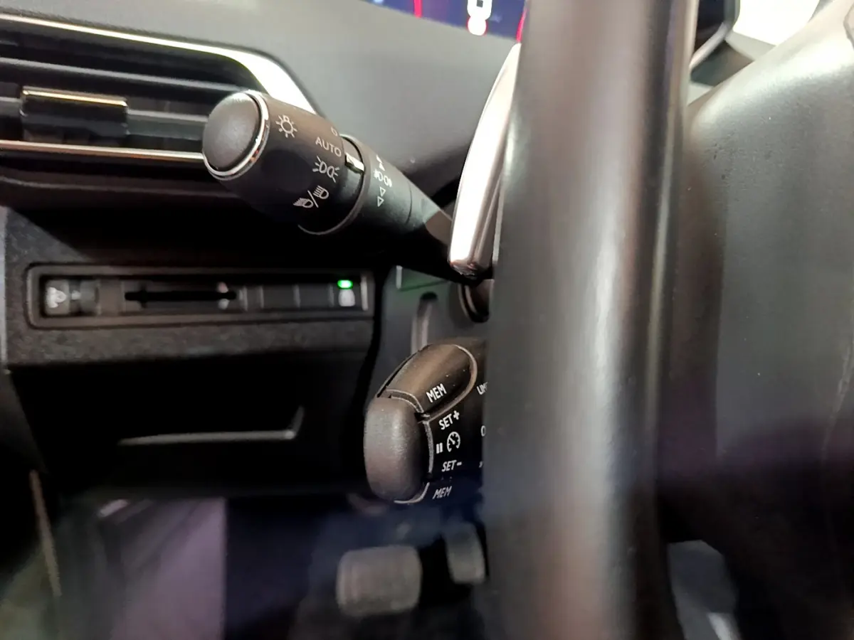 Gros plan sur les commandes au volant et le commodo d'éclairage du Peugeot 5008 gris clair, version 2020 Essence.