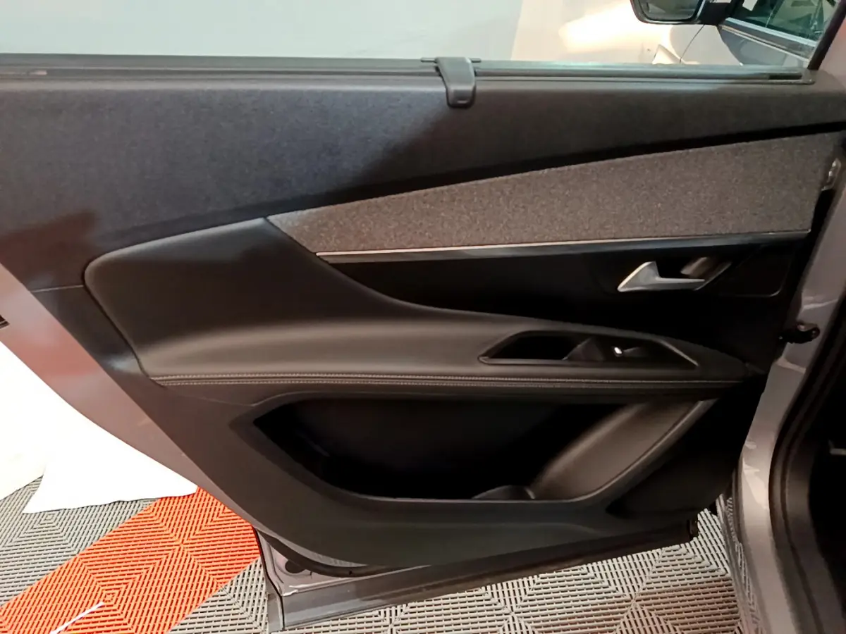 Porte intérieure côté gauche du Peugeot 5008 gris clair, montrant la garniture noire et les commandes de fenêtre.