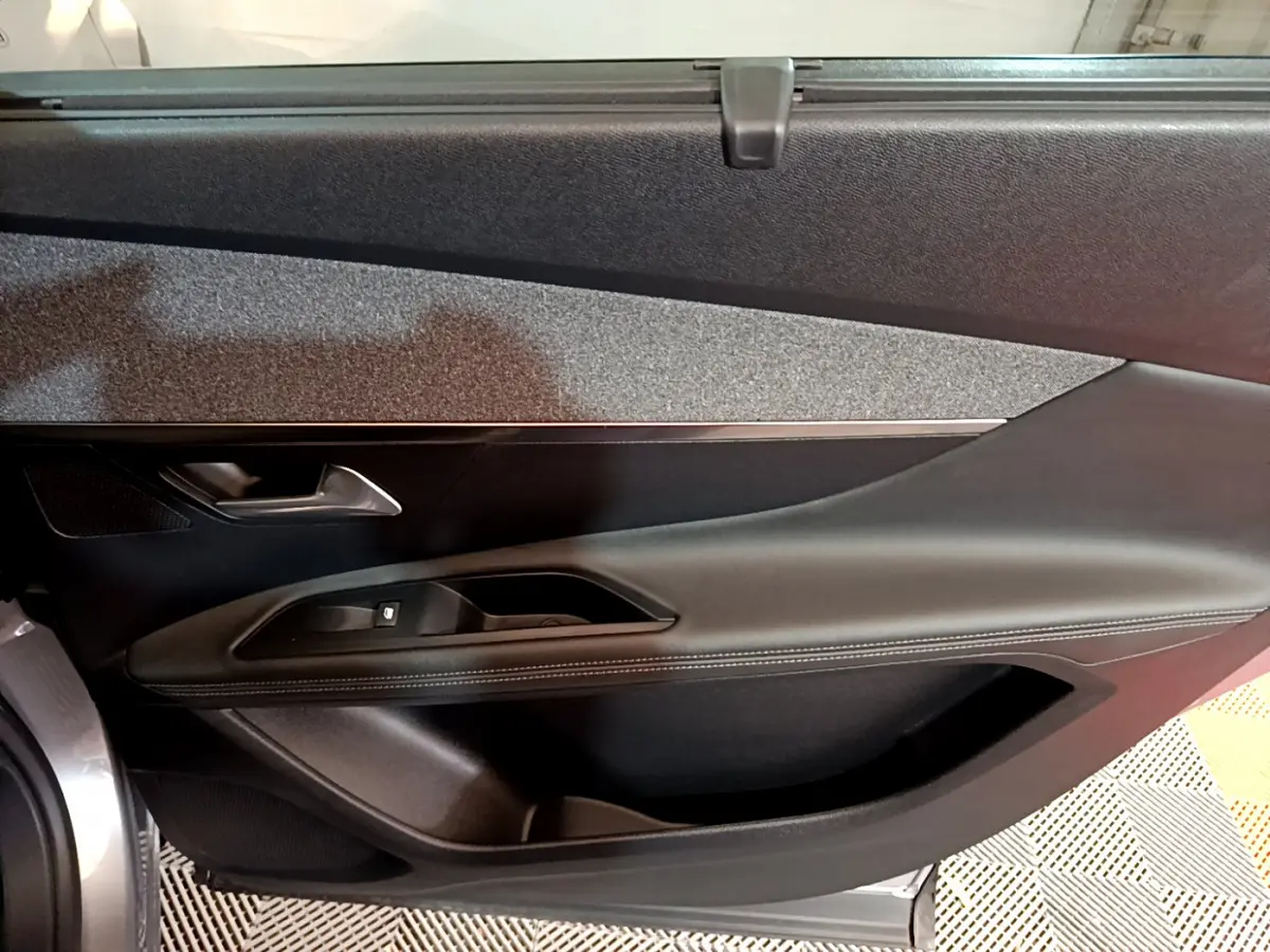 Vue intérieure côté gauche de la porte avant gris clair du Peugeot 5008 avec garniture noire et surpiqûres blanches.