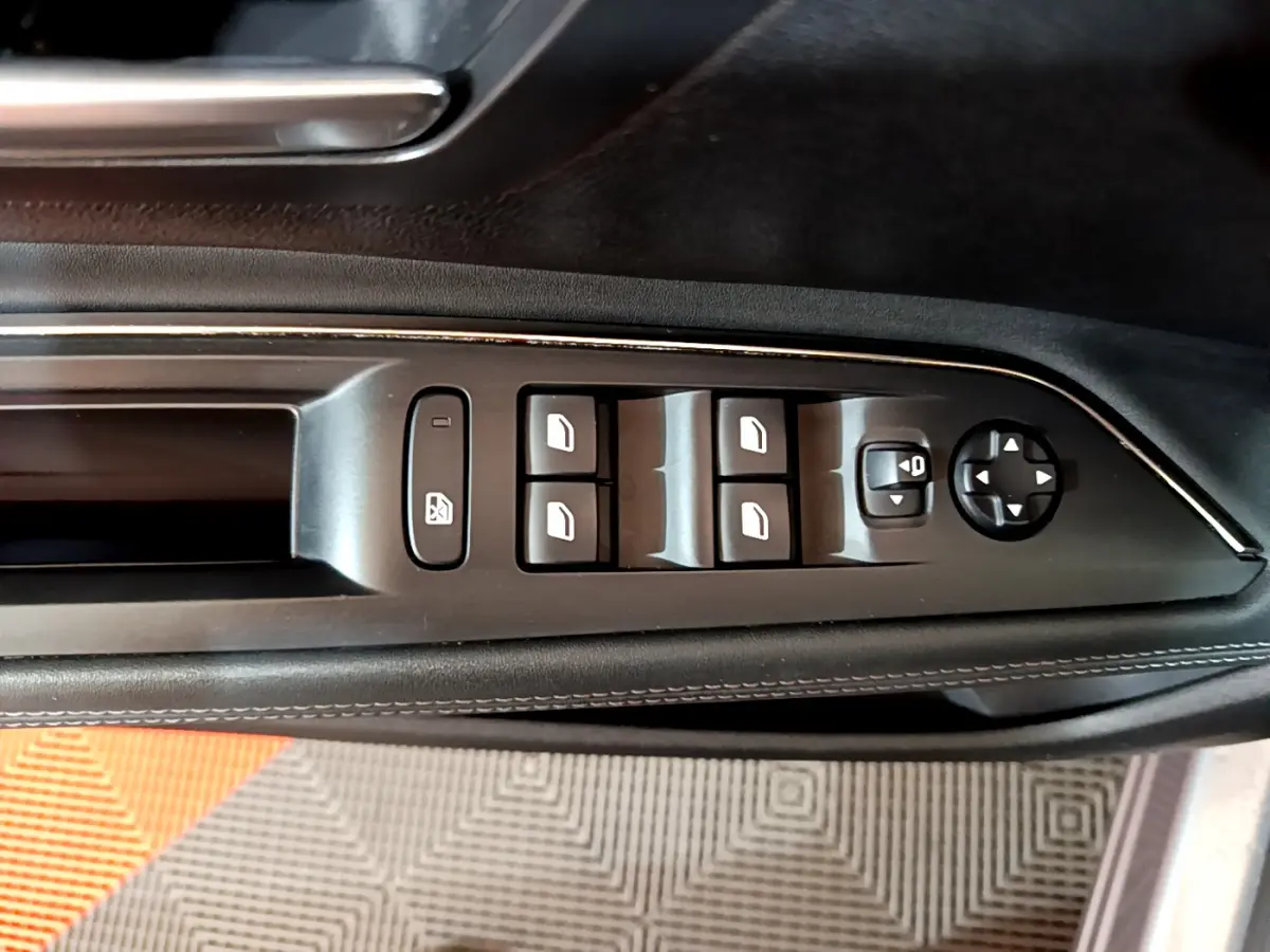 Vue rapprochée des commandes de lève-vitres et rétroviseurs sur la porte côté conducteur d'un Peugeot 5008 gris clair 2020.