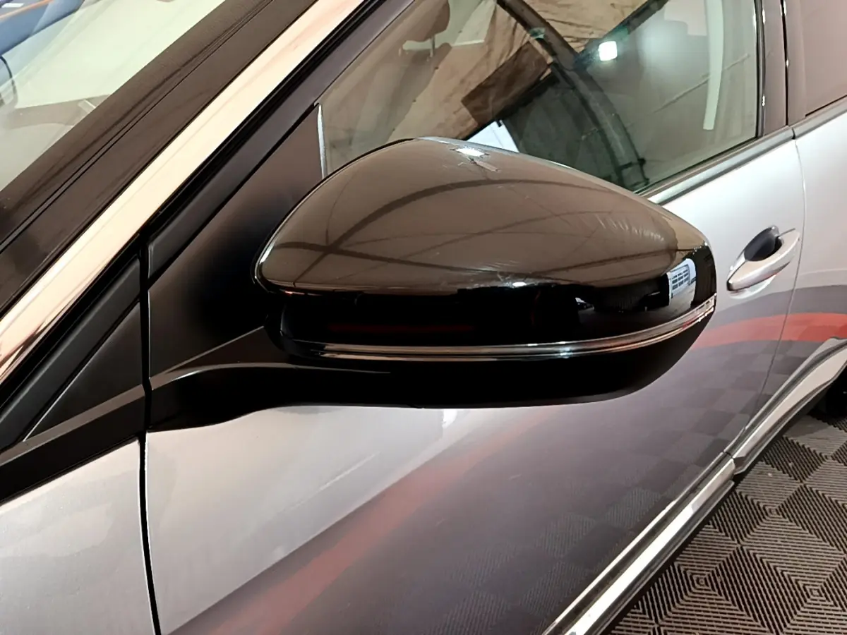 Rétroviseur côté gauche noir brillant sur Peugeot 5008 gris clair, avec poignée de porte visible en arrière-plan.