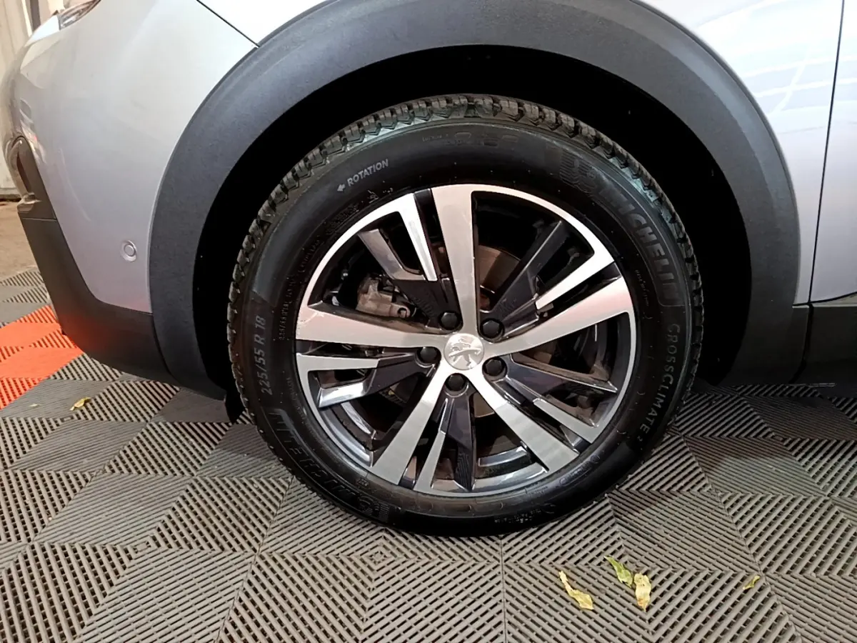 Gros plan sur la roue avant gauche gris clair du Peugeot 5008 avec jante alliage et logo lion central.