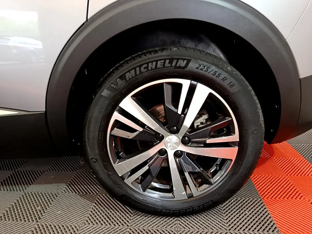 Gros plan sur la roue avant droite du Peugeot 5008 gris clair, jante alliage et pneu Michelin visible.