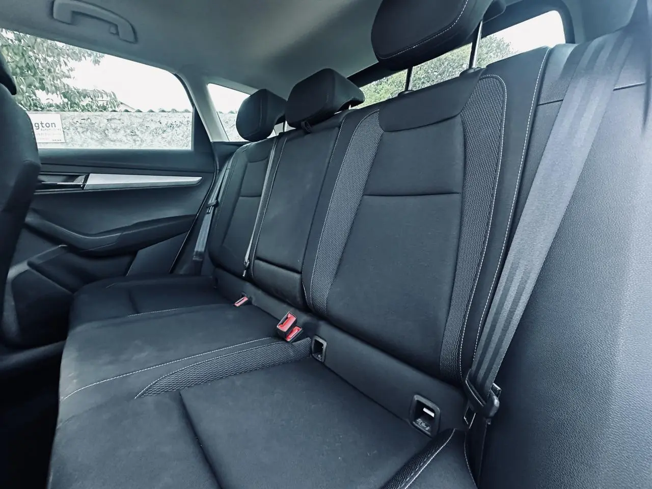 Vue intérieure de la banquette arrière noire du Skoda Karoq 2024, avec ceintures et appuie-têtes visibles.