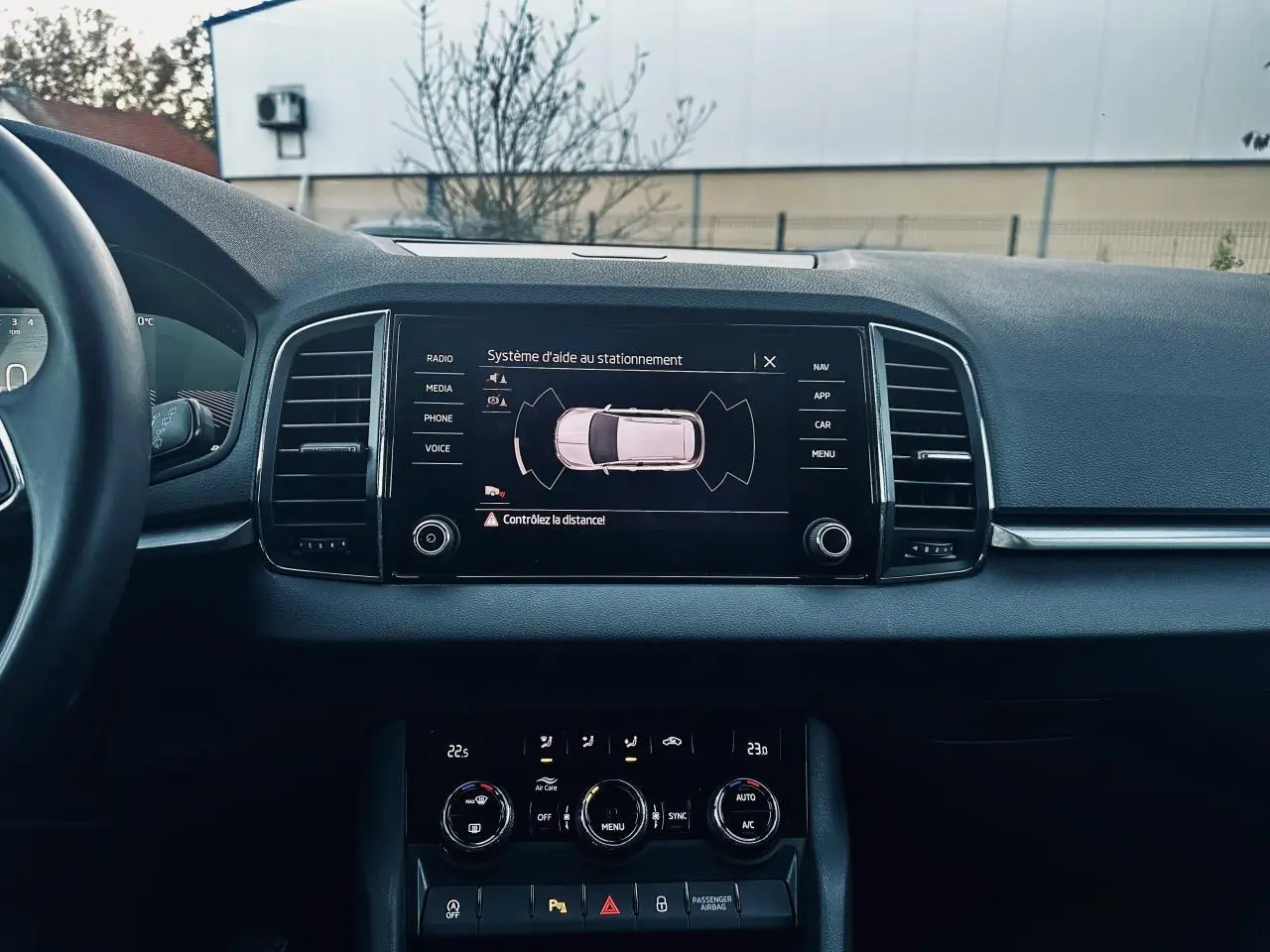 Vue intérieure du tableau de bord du Skoda Karoq 2024 avec écran tactile affichant l'aide au stationnement.
