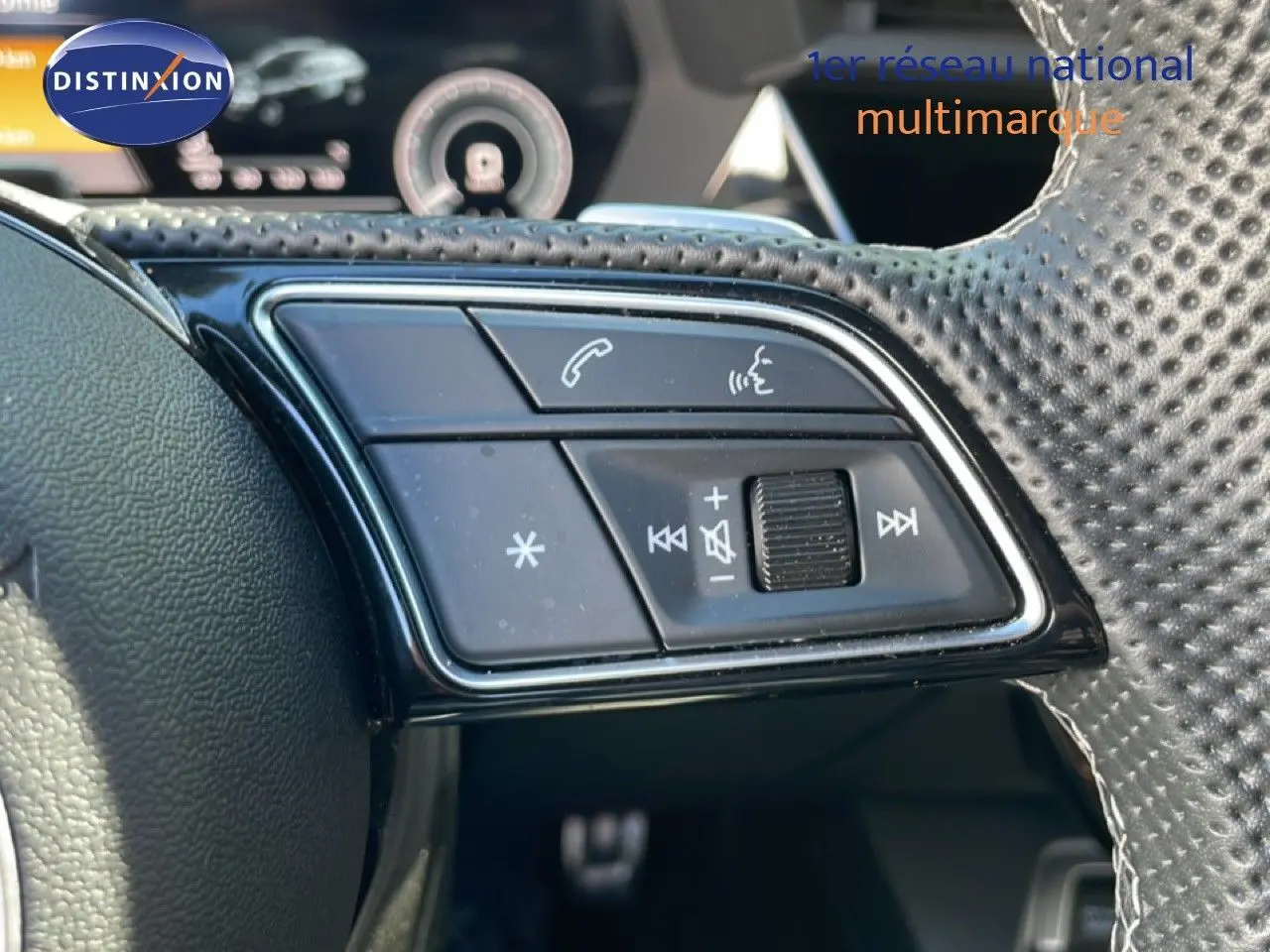 Gros plan sur les commandes gauche du volant perforé de l'Audi A3 Sportback 40 TFSIe bleu Navarre 2025.