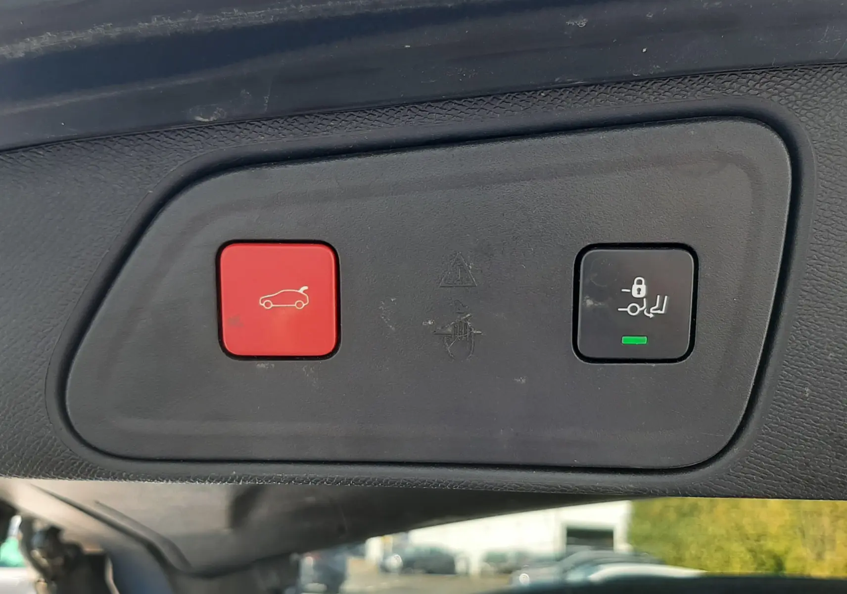 Gros plan sur les boutons de commande du hayon électrique d'un Peugeot 3008 bleu Vertigo, intérieur noir visible en arrière-plan.