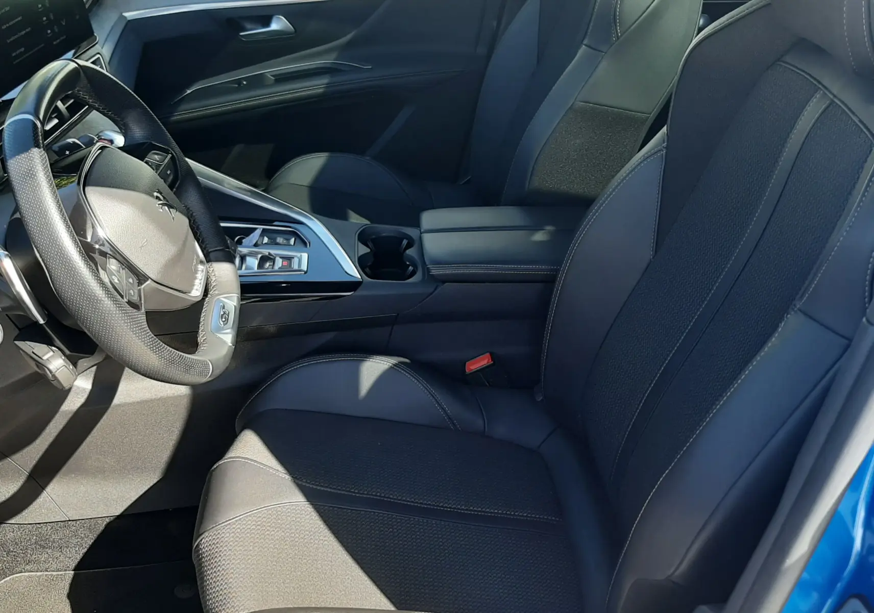 Intérieur avant droit du Peugeot 3008 2023 bleu Vertigo, sièges noirs en cuir et tissu avec console centrale moderne.