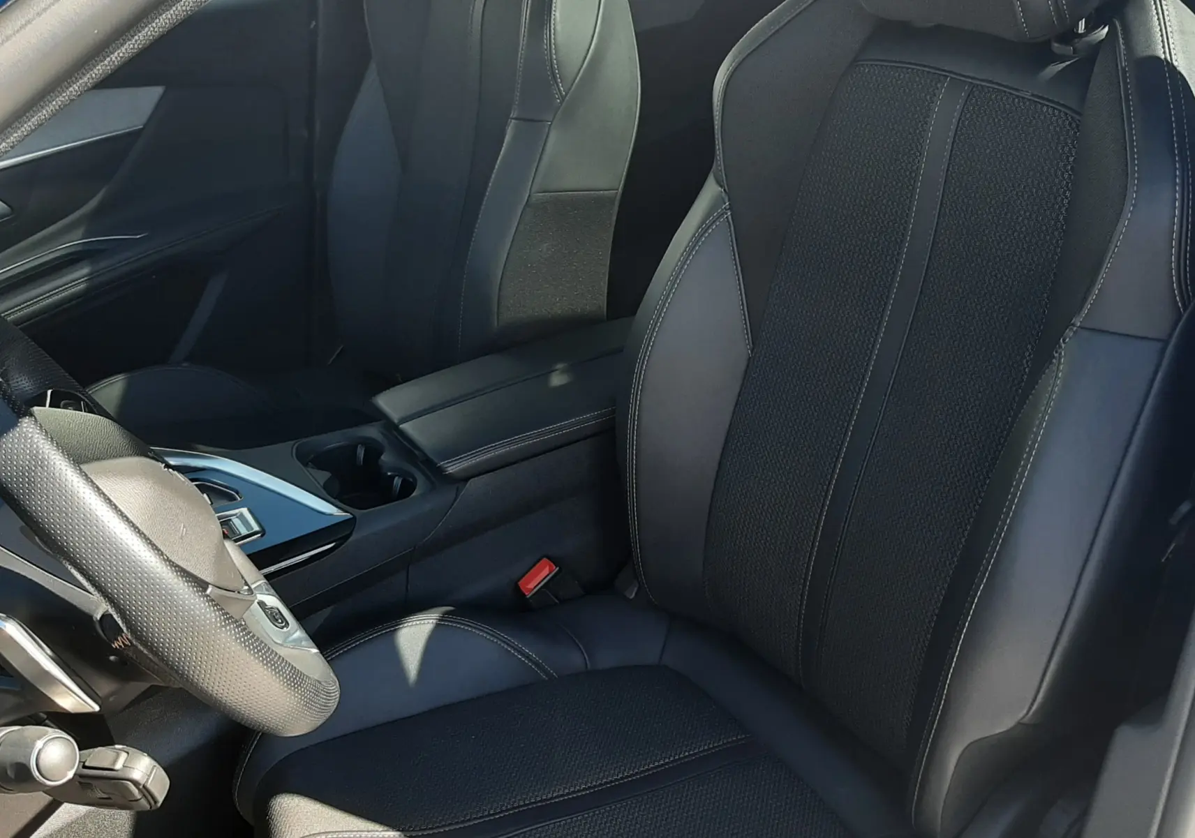 Vue intérieure côté conducteur du Peugeot 3008 2023, sièges en cuir noir avec surpiqûres blanches et console centrale moderne.
