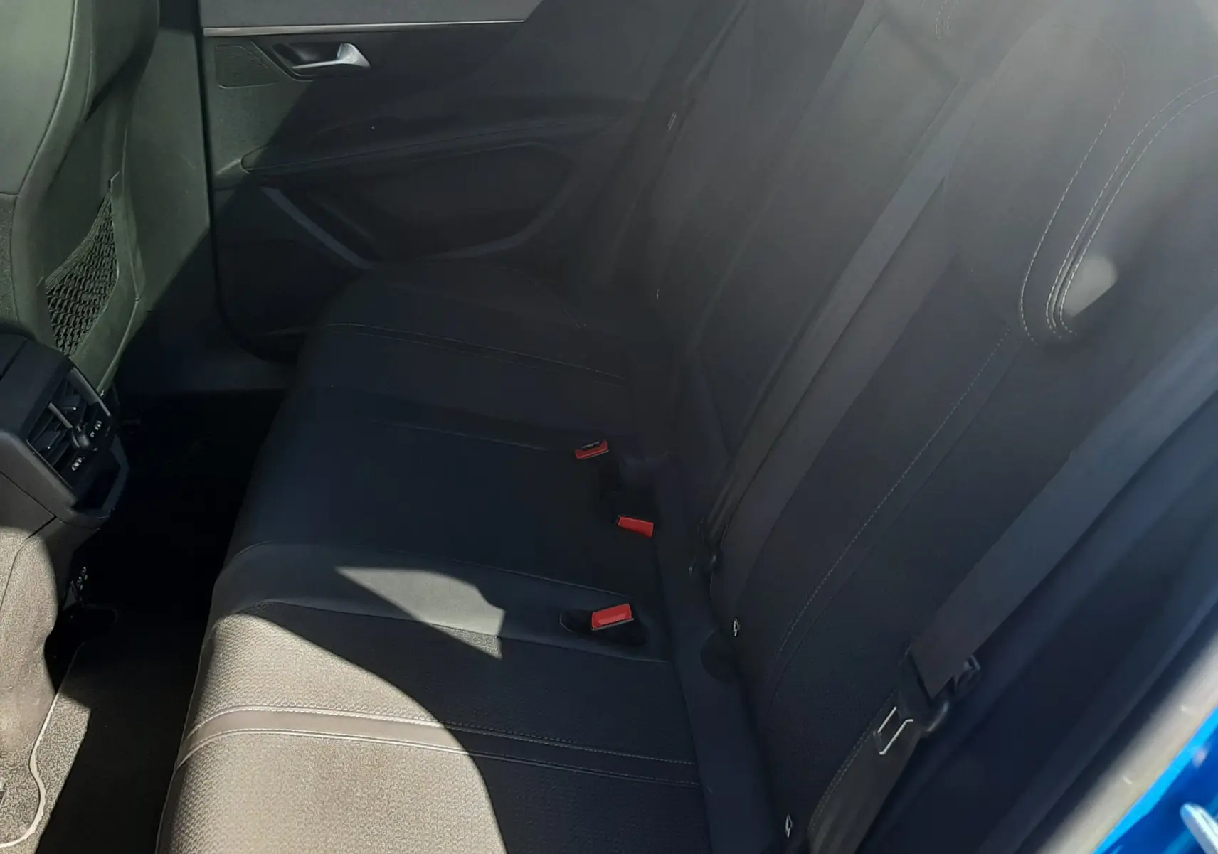 Vue intérieure côté droit des sièges arrière noirs du Peugeot 3008 2023, avec ceinture de sécurité et porte ouverte bleu Vertigo.
