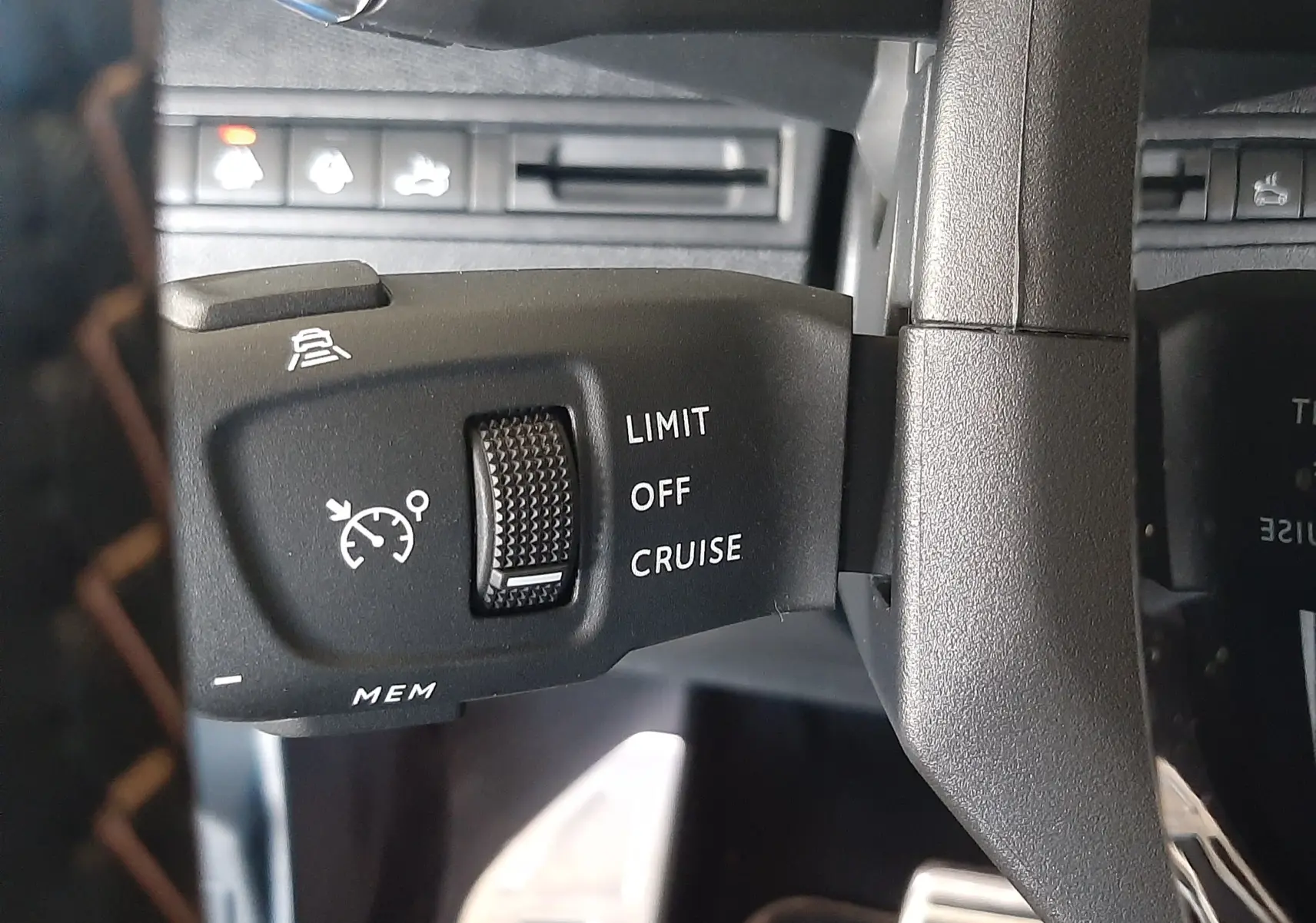 Gros plan sur la commande de régulateur de vitesse à gauche du volant dans l’habitacle noir du Peugeot 3008 2023.