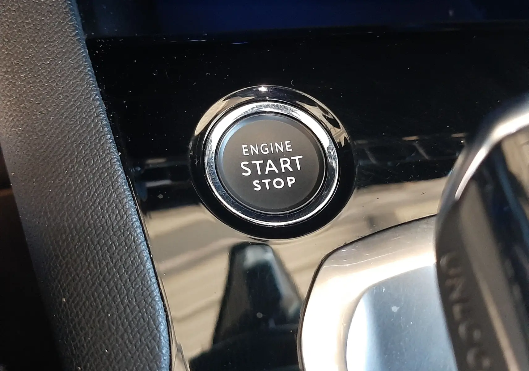 Bouton moteur start/stop en gros plan sur la console centrale noire brillante du Peugeot 3008 GT 2023.