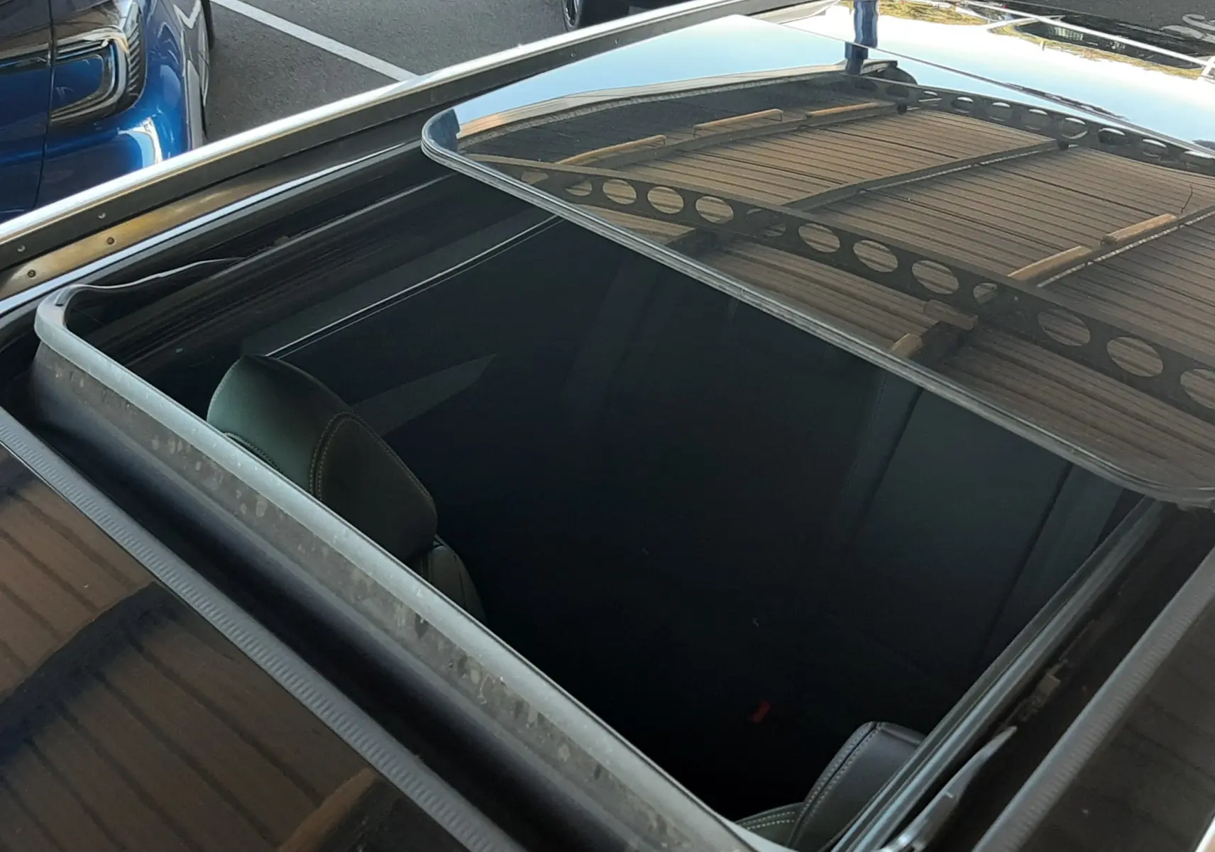 Vue en plongée du toit ouvrant panoramique noir diamant du Peugeot 3008 bleu Vertigo, avec intérieur partiellement visible.