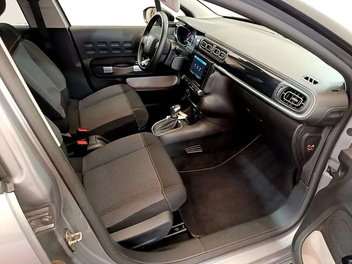 Vue intérieure côté conducteur de la Citroën C3 gris clair 2019 avec tableau de bord moderne et sièges tissu noirs.