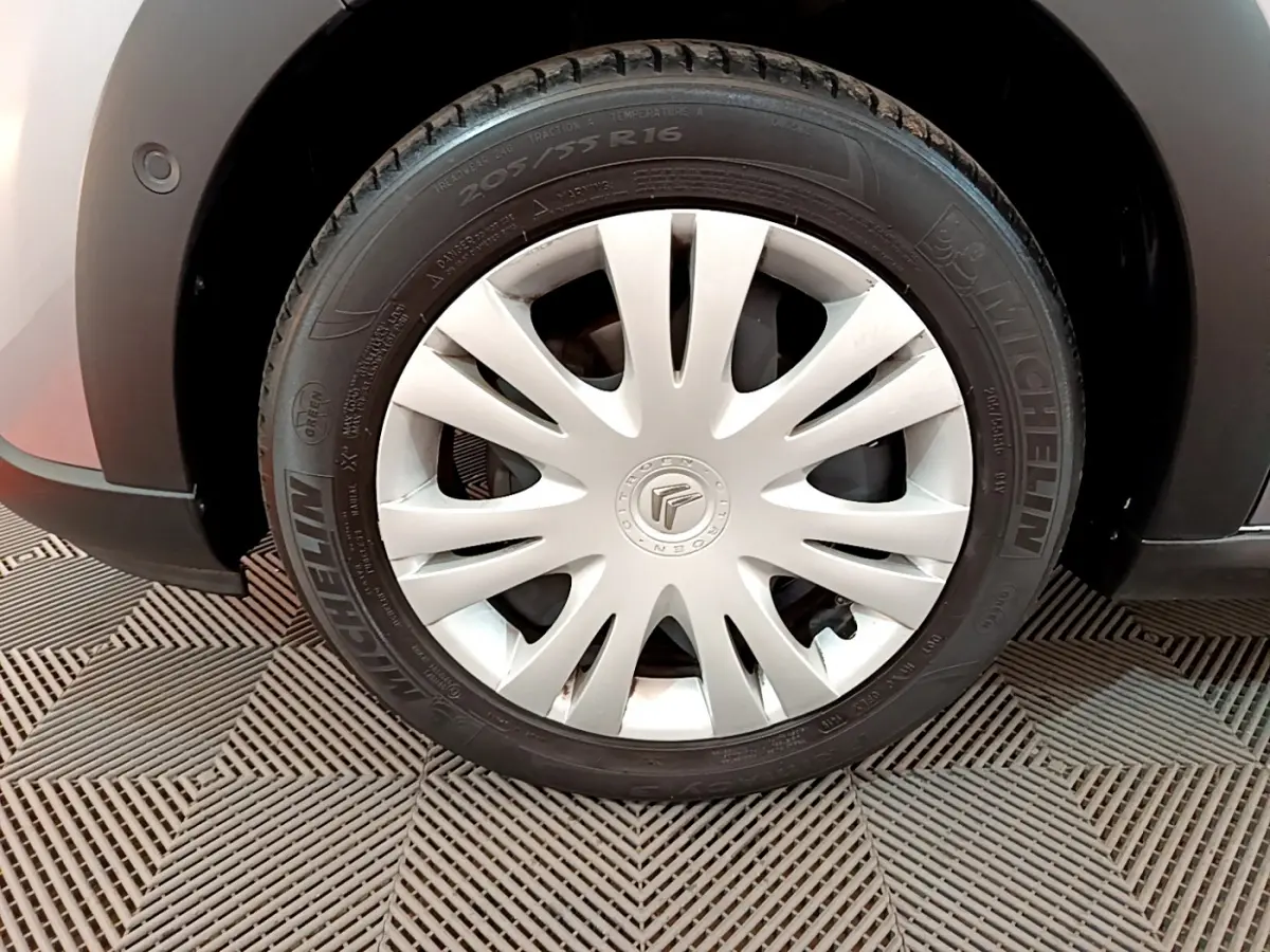 Gros plan sur la roue avant droite grise d'une Citroën C3 2019 avec jante acier et enjoliveur blanc à rayons fins.