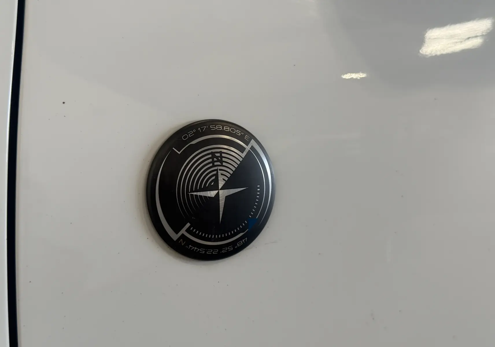 Gros plan sur l'écusson boussole noir et argent sur la carrosserie blanche d'un Peugeot 2008 Crossway 2018.