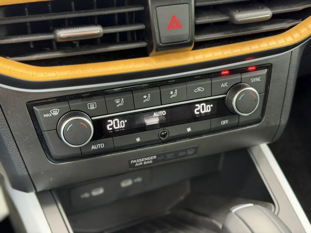 Gros plan sur la console centrale du SEAT Arona blanc, montrant la climatisation automatique bi-zone réglée à 20°C.