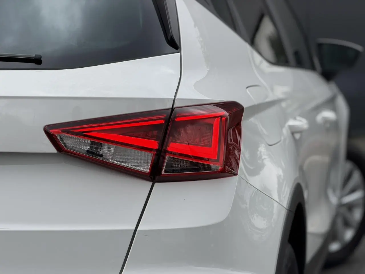 Gros plan sur le feu arrière droit d'un SEAT Arona blanc, mettant en valeur la ligne anguleuse et la carrosserie lisse.