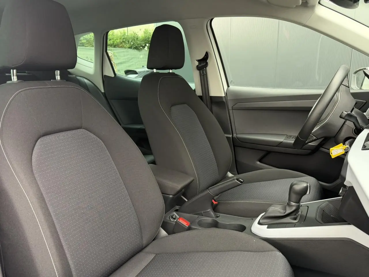 Intérieur avant du SEAT Arona 2025, vue côté droit, sièges tissu gris et console centrale avec boîte automatique.