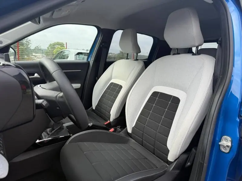 Vue intérieure des sièges avant gris clair et noir d'une Citroën C3 2025, porte ouverte côté conducteur.