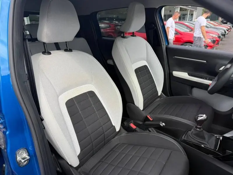 Vue intérieure des sièges avant en tissu clair et noir de la Citroën C3 2025, avec levier de vitesse manuel visible.