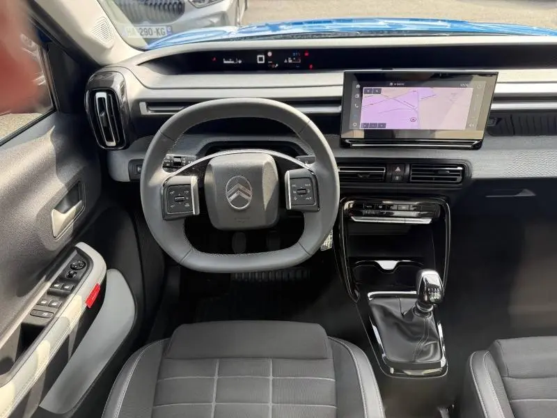 Vue intérieure avant de la Citroën C3 noire 2025, volant multifonction et écran tactile central avec navigation visible.