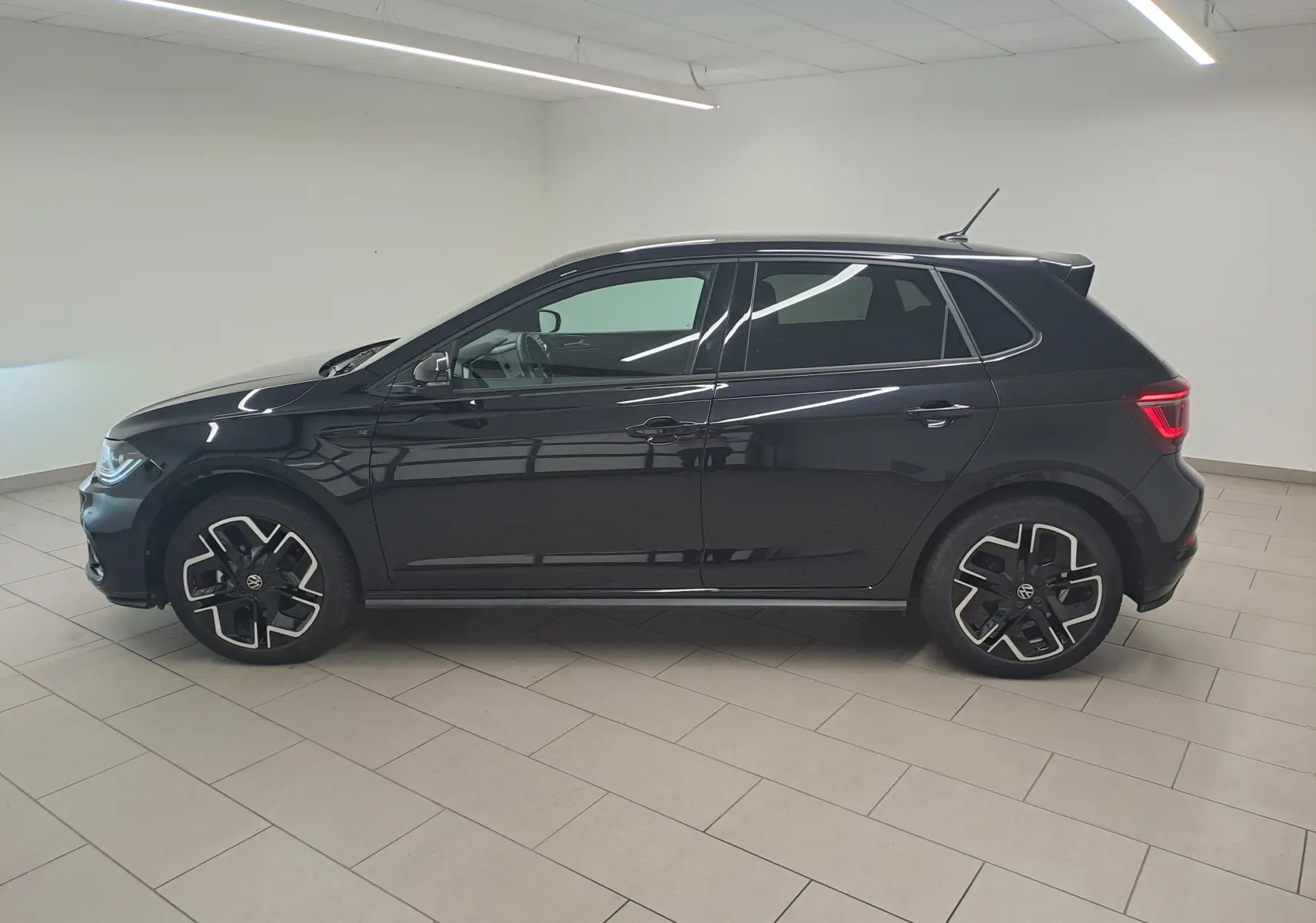Volkswagen Polo 2025 Noir Intense vue de profil côté gauche, jantes noires et détails R-Line visibles.