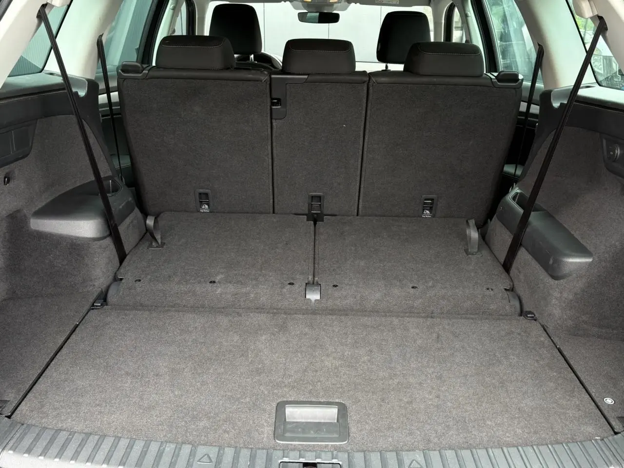 Coffre spacieux du Skoda Kodiaq 1.5 TSI 7 places, vue arrière avec sièges arrière rabattus, intérieur gris.