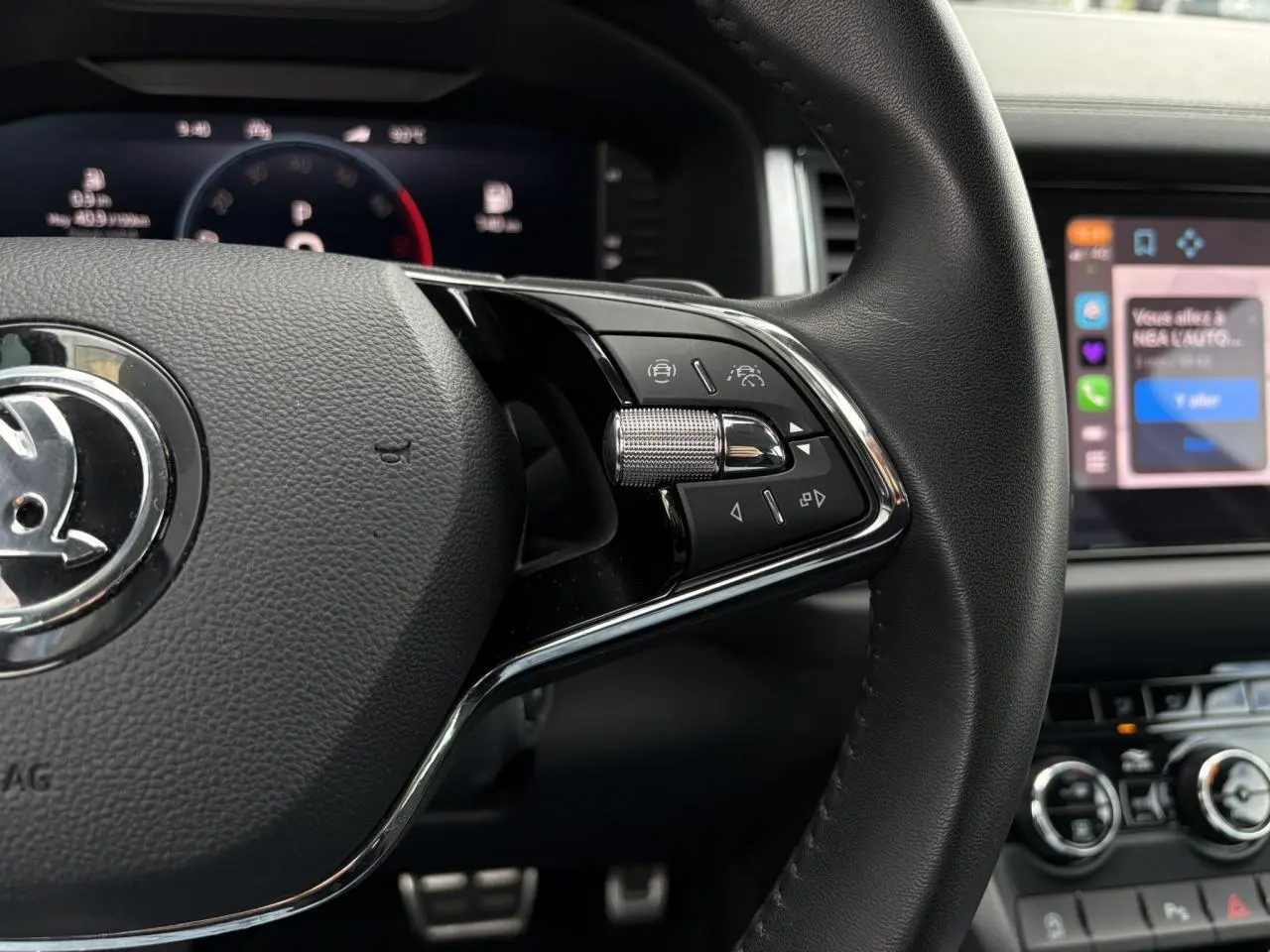 Gros plan sur la partie droite du volant noir du Skoda Kodiaq 2024 avec commandes intégrées et tableau de bord numérique en arrière-plan.